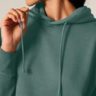 Sweat femme en coton biologique de couleur vert jade avec un dessin représentant les cinq éléments dans le dos de sérigraphie beige.