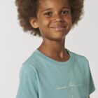 Tshirt enfant manche courte en coton biologique. De couleur turquoise avec le dessin d'une baleine et des motifs polynésiens. La couleur de la sérigraphie est beige.