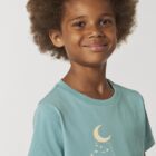 Tshirt enfant en coton biologique manche courte de couleur turquoise avec le dessin d'un arbre et d'un cerf volant avec une sérigraphie de couleur beige.
